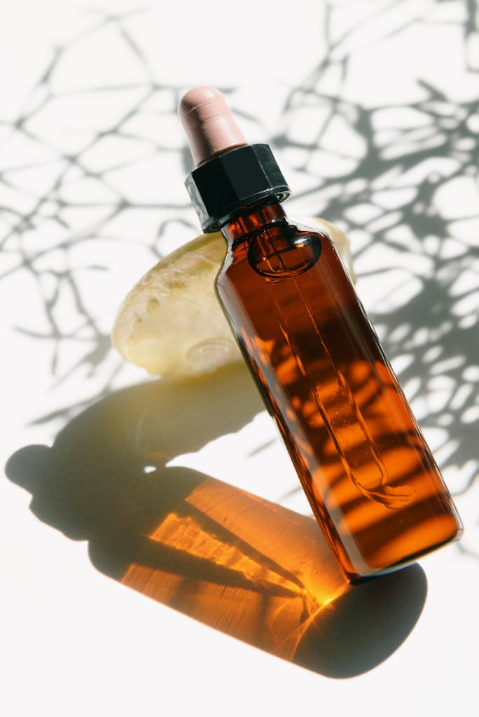 A sleek glass aromatherapy bottle casting artistic shadows, perfect for skincare or wellness themes.